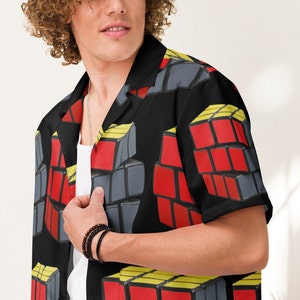 May include: A black short-sleeved button-up shirt with a repeating pattern of a red, yellow, and gray Rubik's Cube.