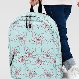 May include: A light blue backpack with a floral pattern. The flowers are red and white and have a simple, hand-drawn style.