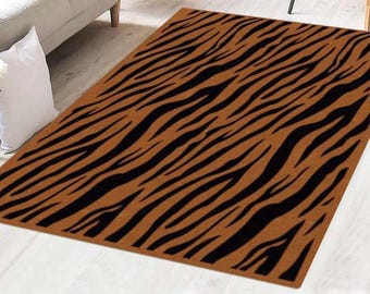 May include: A rectangular rug with a brown background and black zebra stripe pattern. The rug is placed on a light-colored wooden floor, with a sofa and a white pillow in the background. The rug adds a touch of animal print to the room.