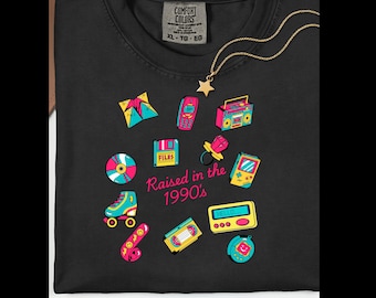 May include: Black Comfort Colors t-shirt with a gold star necklace. The shirt features colorful 90s-themed graphics including a boombox, roller skates, and the text "Raised in the 1990's".