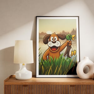 Puede incluir: Una lámina de arte mural enmarcada que muestra a un perro marrón de estilo caricatura emergiendo de hierba alta verde. El perro tiene una expresión alegre y sostiene a un pato marrón y blanco por el cuello. El fondo muestra un lago al atardecer.