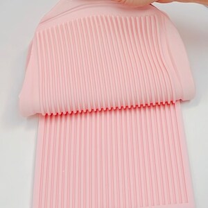 Peut inclure: Un moule en silicone rose clair avec un motif nervuré. Le moule est souple et semble être utilisé pour créer des surfaces ou des motifs texturés. Le motif nervuré est uniforme sur toute la surface.
