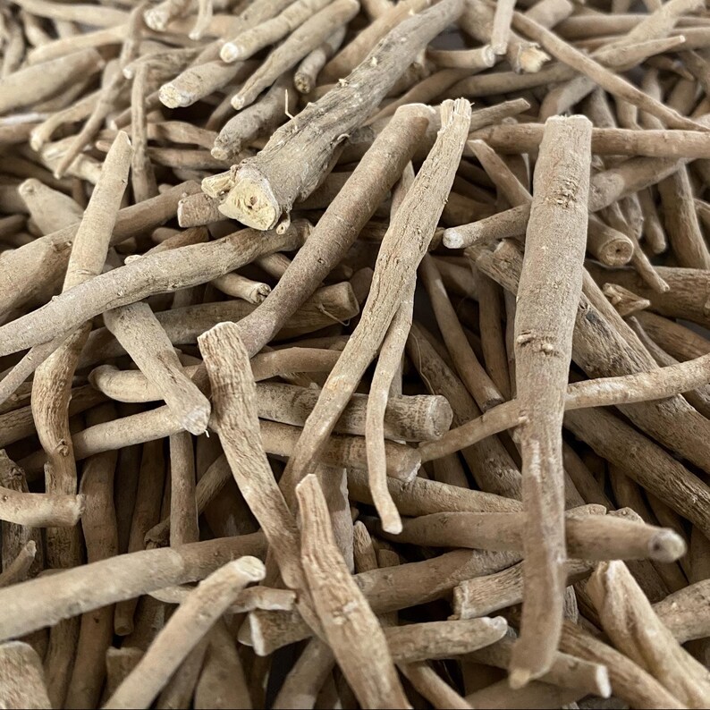 May include: Close-up of a pile of dried, light brown ashwagandha roots. The roots vary in size and shape, with a rough, textured appearance. The image is well-lit, highlighting the natural color and details of the herbal product.