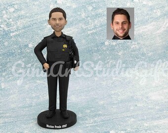 May include: A black and white custom bobblehead figurine of a police officer. The figurine is wearing a black uniform with a badge and a name tag that reads "Maxime Proulx #927".