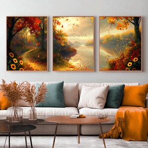 May include: Three framed art prints showcasing autumnal scenes. The artworks feature vivid reds, oranges, and yellows, with trees, a winding path, and a river. Sunflowers and falling leaves enhance the seasonal theme. The prints are displayed above a sofa.