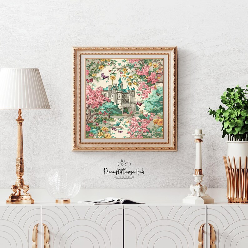 K&ouml;nnte beinhalten: Ein gerahmter Druck mit einer Schlossszene, umgeben von rosa und gelben Blumen, Schmetterlingen und B&auml;umen. Das Schloss hat blaue T&uuml;rme und ist vor einem cremefarbenen Hintergrund platziert. Der Rahmen ist goldfarben. Der Druck wird auf einem wei&szlig;en Schrank ausgestellt.