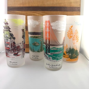 May include: Four vintage frosted glass tumblers with colorful illustrations of landmarks. One features Chinatown, San Francisco, another Lake Tahoe, Emerald Bay, the Golden Gate Bridge, and Arizona "Yucca". Each glass has a different design.