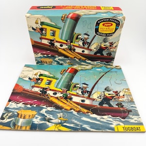 Peut inclure: Puzzle de personnages Disney vintage représentant une scène de remorqueur avec Donald Duck et Dingo. Le puzzle est dans une boîte avec le logo Jaymar et les mots "Bantam Pocket Picture Puzzle". Le puzzle est partiellement assemblé.