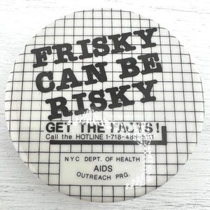 May include: A round, white button with a black grid pattern and bold black text that reads "FRISKY CAN BE RISKY." Below, it says "GET THE FACTS!" and a hotline number. The bottom reads "NYC DEPT. OF HEALTH AIDS OUTREACH PRG."