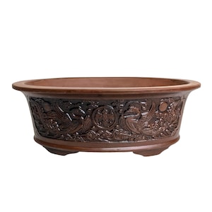 May include: A brown ceramic bonsai pot with an intricate design of stylised birds and clouds around the rim.
