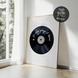 May include: A framed print featuring a black vinyl record design. The record has the text "if it's nice play it twice" in white script. The print is in a light wood frame and is leaning against a wall near a window.