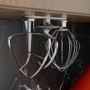 May include: Two silver kitchen mixer attachments hanging from a cupboard. The attachments are a dough hook and a whisk.