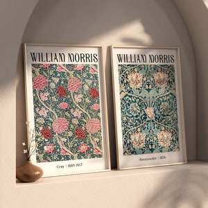 May include: Two framed prints of William Morris floral designs. The left print features a pink and green floral pattern with the text "Cray | 1887-1917". The right print features a blue and green floral pattern with the text "Honeysuckle | 1876".
