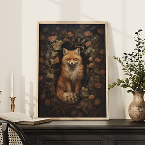 May include: A framed print of a red fox sitting in a wreath of flowers and leaves. The fox has a white chest and a bushy tail. The background is dark and the flowers are in shades of pink and white.
