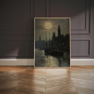Puede incluir: Una pintura enmarcada que representa una ciudad nocturna con luna llena en el cielo. La ciudad se recorta contra el cielo iluminado por la luna, con un r&iacute;o en primer plano y varios barcos atracados a lo largo de la orilla.