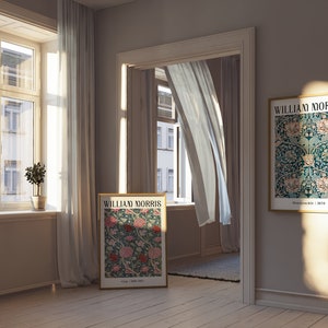 May include: Two framed posters with a floral pattern and the text "William Morris" in a light brown room with white curtains and a small potted plant.