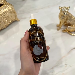 Op de afbeelding: Een bruine glazen fles met een gouden dop en een witte druppelaar. Het etiket leest "Cherry Vanilla" met een illustratie van een kers en slagroom. De fles wordt in een hand gehouden.