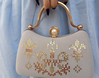 Bolso de mano con emblema dorado: bolso de noche de ante color marfil bordado.