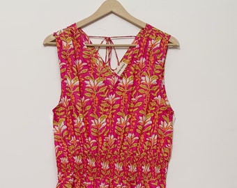 May include: A pink sleeveless maxi dress with a floral print in shades of yellow, white, and orange. The dress has a gathered waist and a tiered skirt.