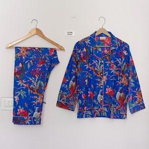 May include: Blue pajama set with a floral and bird print. The set includes a button-down shirt and pants, both with white trim. The text "FUTURE TEXTILE" is visible on the wall.
