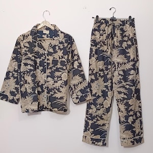 May include: A black and beige pajama set with a floral print. The top has a button-up front and long sleeves. The pants have a drawstring waist and a relaxed fit.