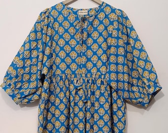 Puede incluir: Un vestido de estampado floral azul y amarillo con un lazo en el escote. El vestido tiene una falda fruncida y mangas 3/4. El vestido está colgado en una percha de madera. La etiqueta del vestido dice "Future Textile".