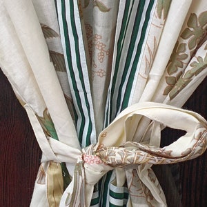 May include: A white cotton robe with green and white striped trim. The robe is tied at the waist and features a floral print.