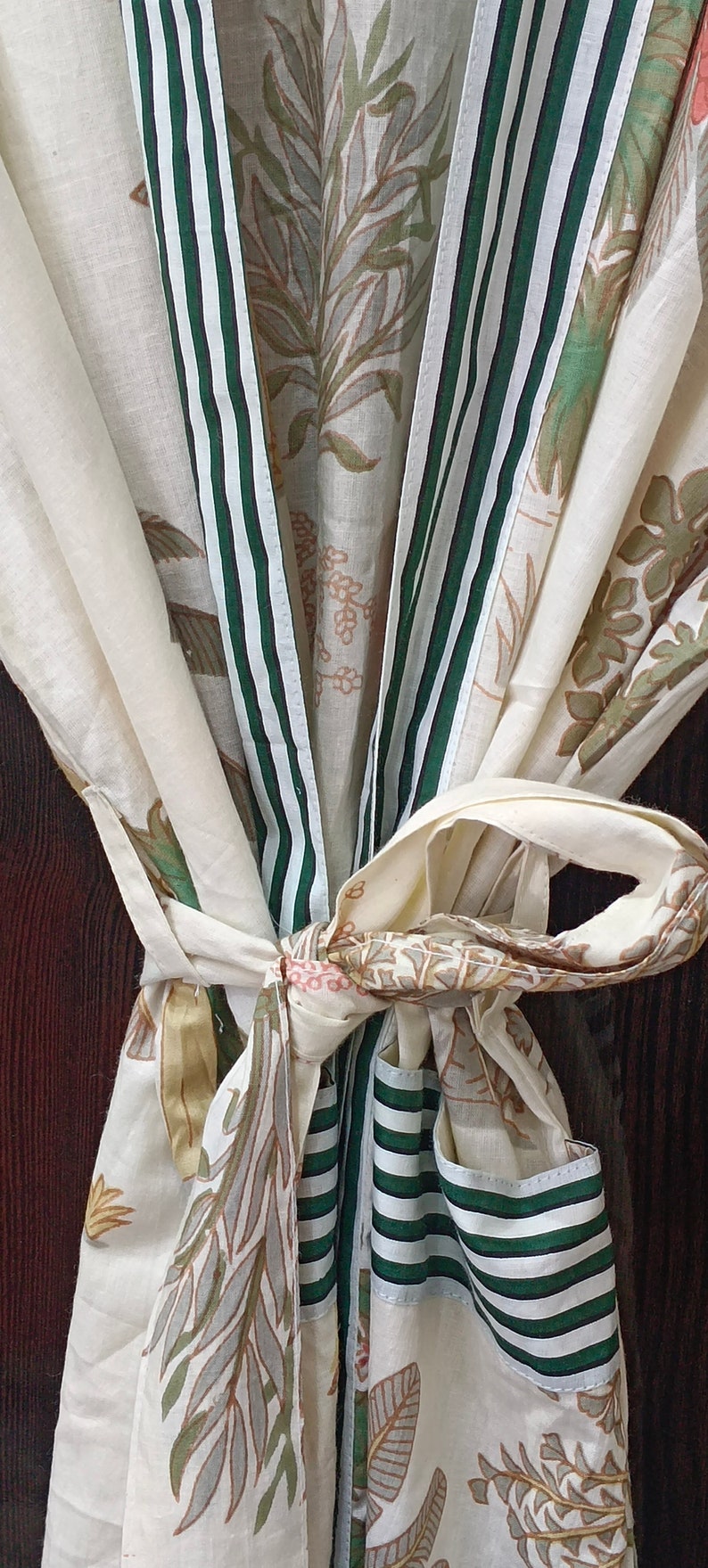 May include: A white cotton robe with green and white striped trim. The robe is tied at the waist and features a floral print.