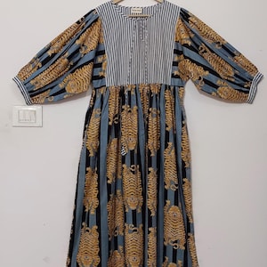 May include: A blue and black striped dress with a tiger print. The dress has a gathered waist and long sleeves with puffed shoulders.