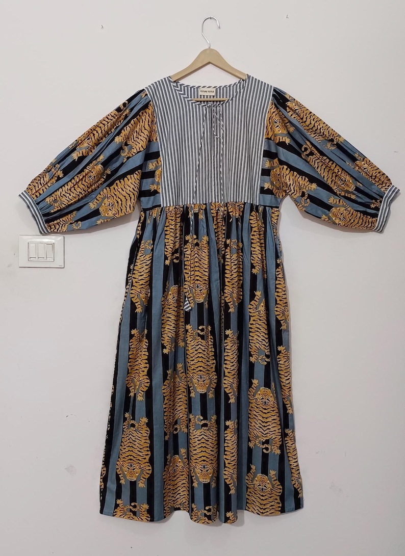 May include: A blue and black striped dress with a tiger print. The dress has a gathered waist and long sleeves with puffed shoulders.