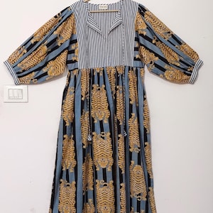 May include: A blue and white striped dress with a tiger print. The dress has a v-neck and long sleeves with a gathered waist.