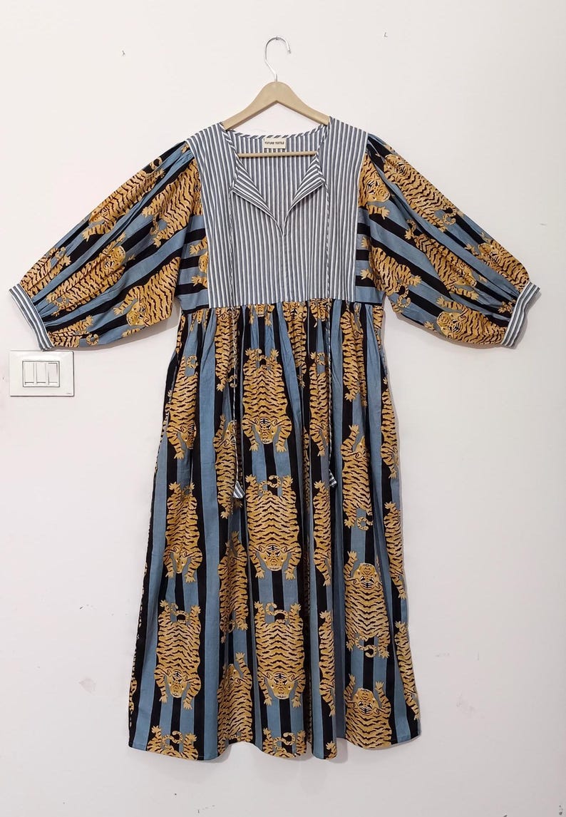 May include: A blue and white striped dress with a tiger print. The dress has a v-neck and long sleeves with a gathered waist.