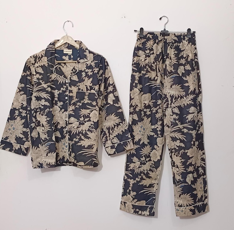 May include: A black and beige pajama set with a floral print. The top has a button-up front and long sleeves. The pants have a drawstring waist and a relaxed fit.