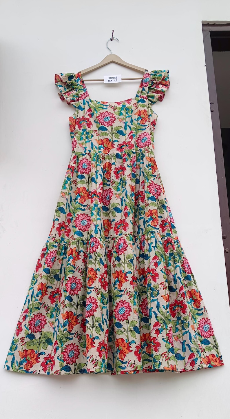 May include: A tiered maxi dress with a floral print in shades of pink, red, orange, blue, and green. The dress has a square neckline and ruffled straps. The dress is hanging on a hanger with a tag that reads "Future Textile".
