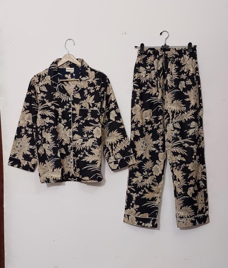 May include: A black and beige pajama set with a floral print. The top has a button-up front and long sleeves. The pants have an elastic waistband.