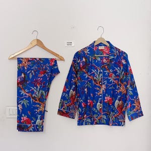 May include: Blue pajama set with a floral and bird print. The set includes a button-down shirt and pants, both with white trim. The text "FUTURE TEXTILE" is visible on the wall.