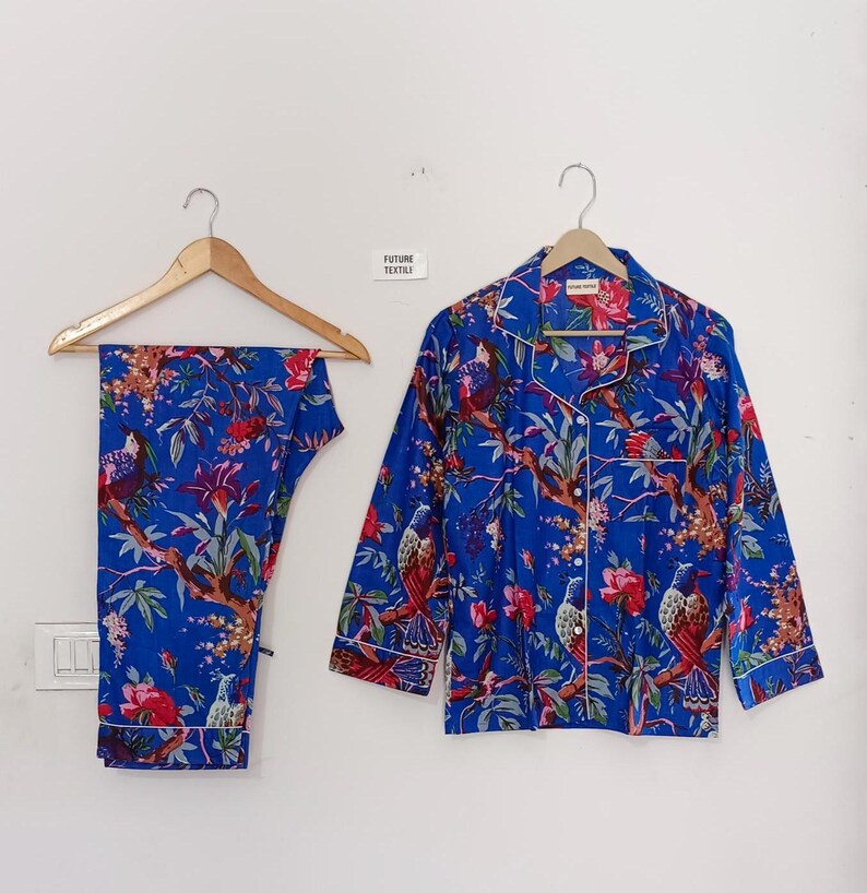 May include: Blue pajama set with a floral and bird print. The set includes a button-down shirt and pants, both with white trim. The text "FUTURE TEXTILE" is visible on the wall.