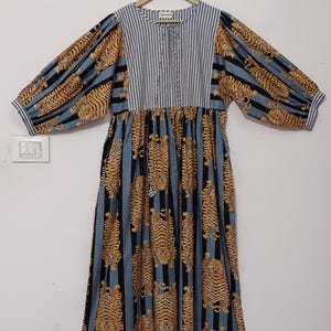 May include: A blue and black striped dress with a tiger print. The dress has a gathered waist and long sleeves with puffed shoulders.