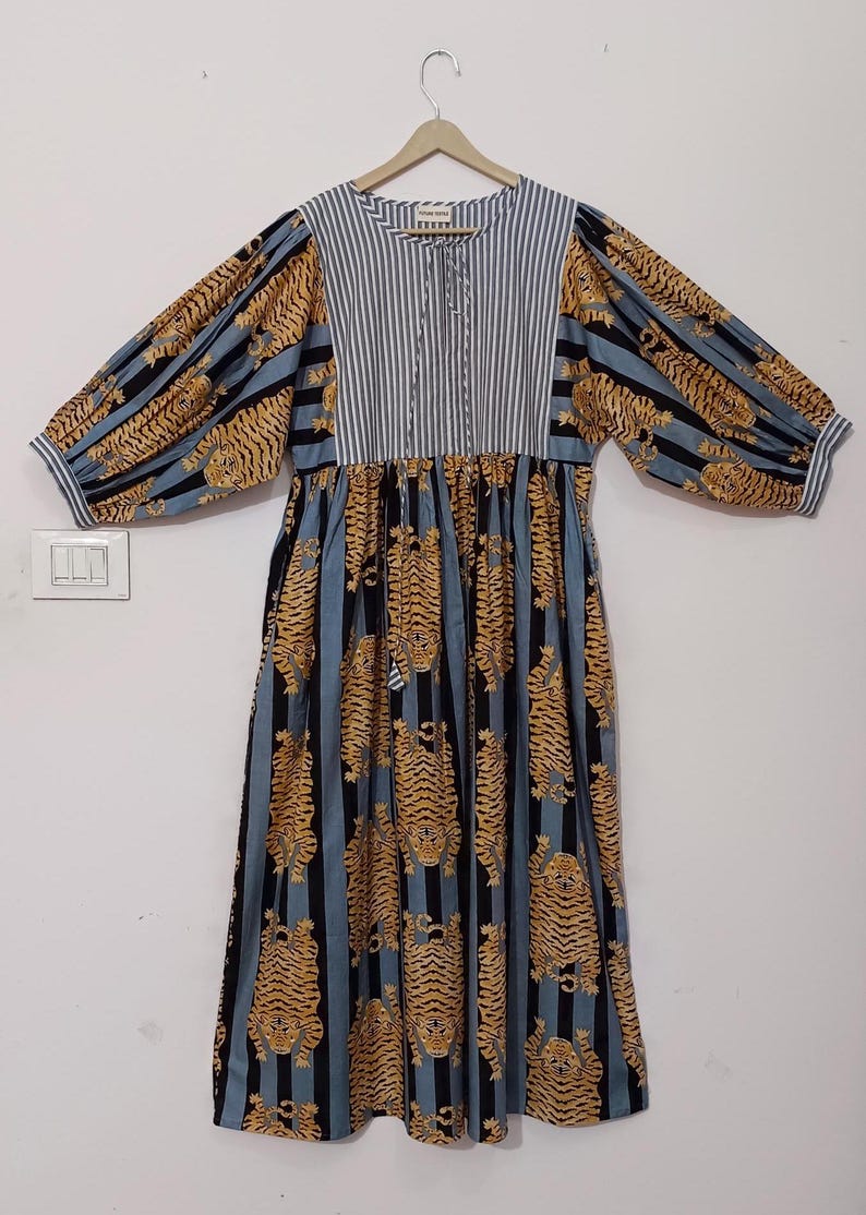 May include: A blue and black striped dress with a tiger print. The dress has a gathered waist and long sleeves with puffed shoulders.