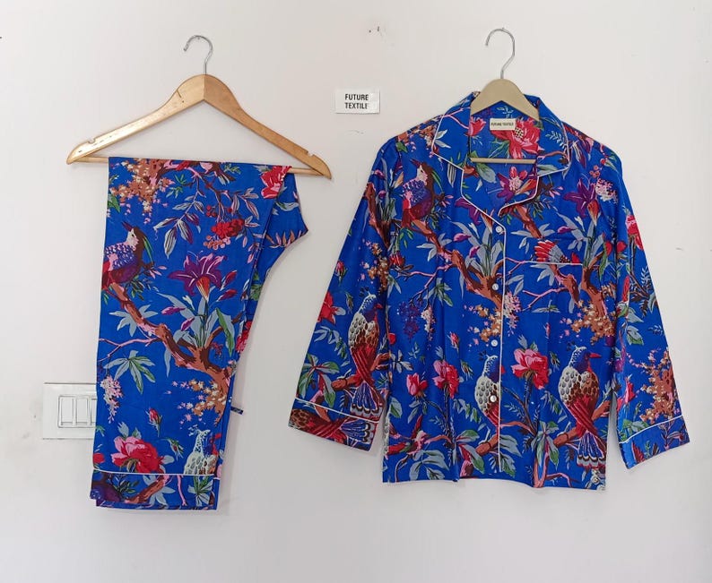May include: Blue pajama set with a vibrant floral and bird print. The set includes a button-down shirt and matching pants. The shirt has white piping and the text "FUTURE TEXTILY".