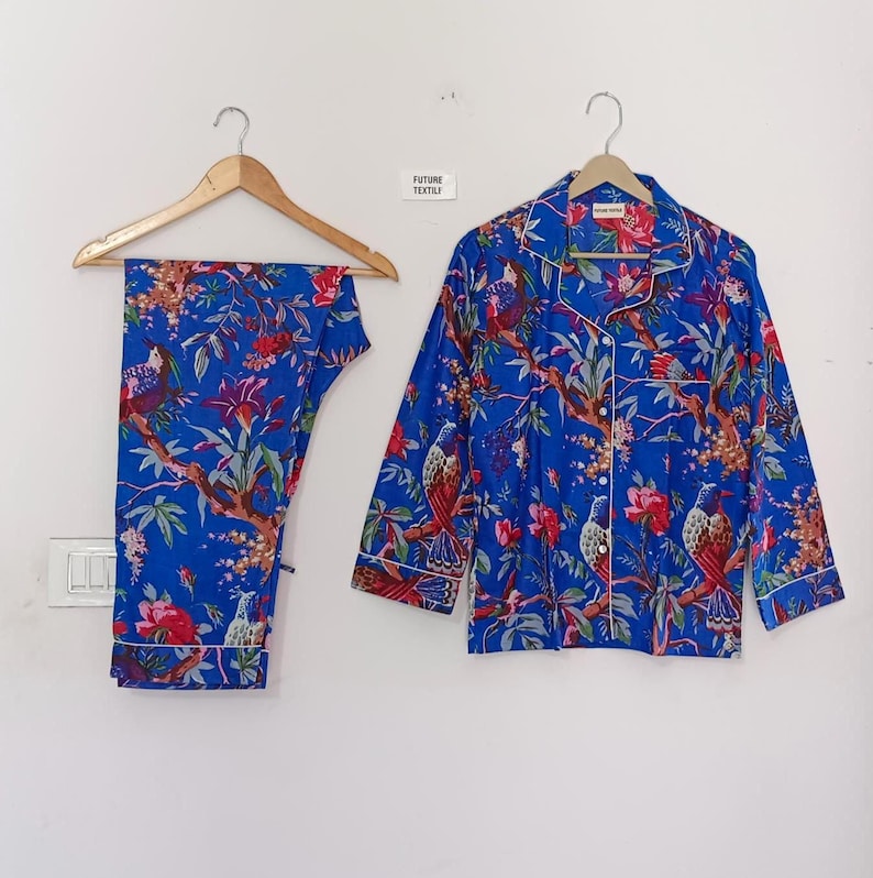 May include: Blue pajama set with a floral and bird print. The set includes a button-down shirt and pants, both with white trim. The text "FUTURE TEXTILE" is visible on the wall.