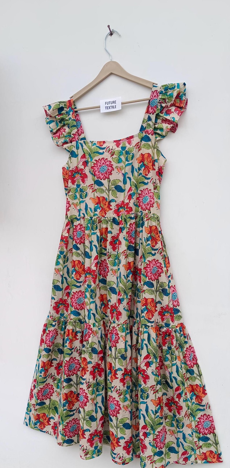 May include: A cream-colored midi dress with a floral print in shades of red, pink, blue, and green. The dress has a square neckline, ruffled straps, and a tiered skirt.