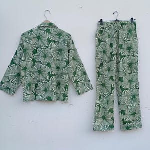 K&ouml;nnte beinhalten: Ein gr&uuml;nes und wei&szlig;es Pyjama-Set mit Blumenmuster. Das Oberteil hat einen Knopfleisten vorne und lange &Auml;rmel. Die Hose hat einen elastischen Bund.