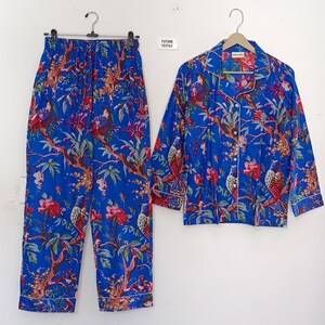 May include: Blue pajama set with a vibrant floral and bird print. The set includes a button-down shirt and matching pants. The fabric features red flowers, brown branches, and white trim. The pajamas are displayed on a white background.