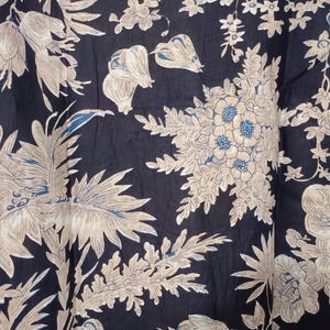 May include: Black fabric with a white floral pattern. The fabric has a soft, flowing texture and is perfect for creating garments or home decor.