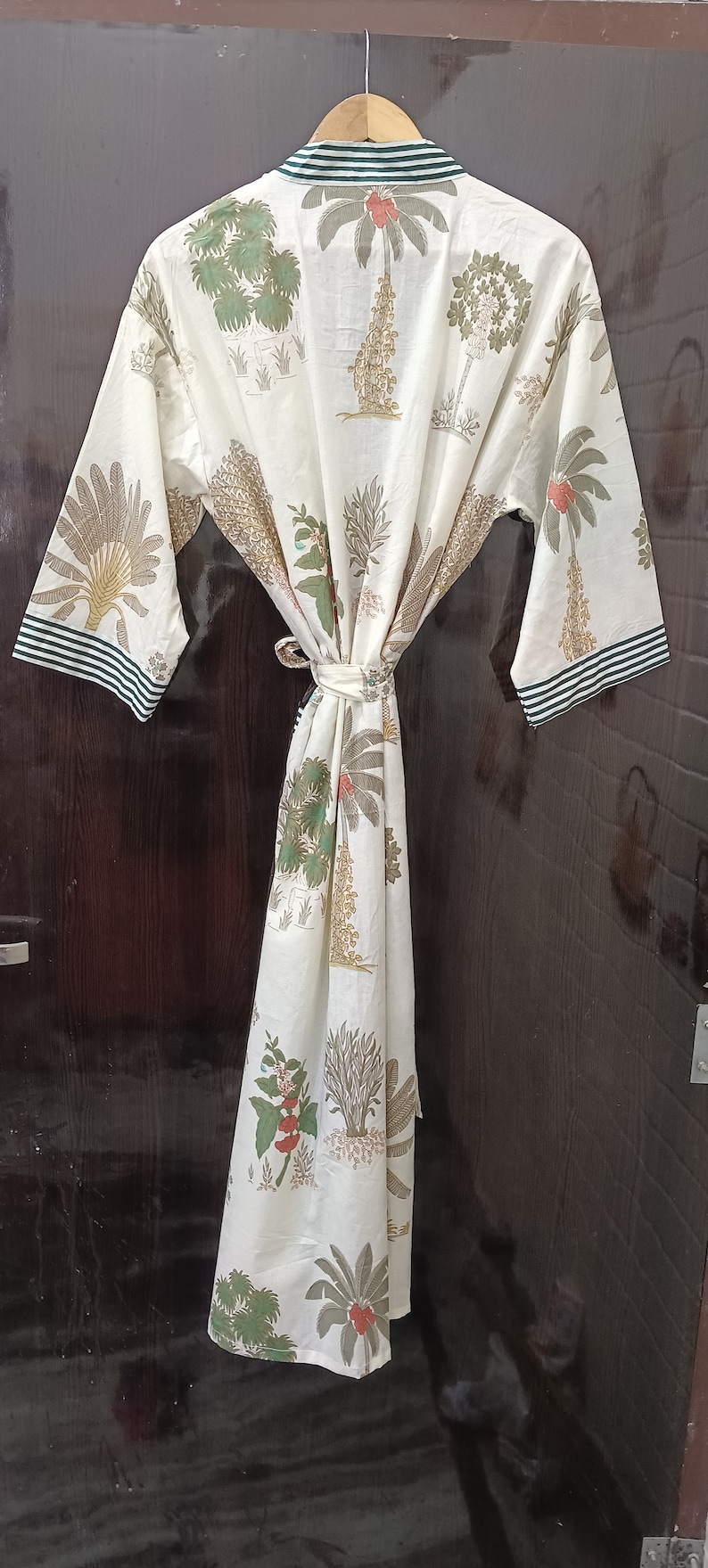 May include: A white cotton robe with a green and brown floral print. The robe has a tie belt and green and white striped trim on the sleeves.