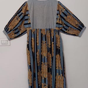 May include: A blue and white striped dress with a tiger print. The dress has a gathered waist and long sleeves.
