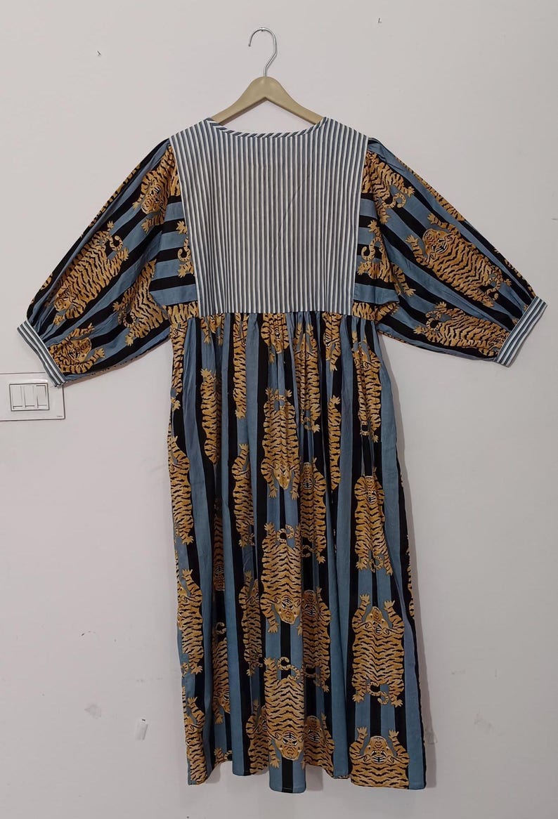May include: A blue and white striped dress with a tiger print. The dress has a gathered waist and long sleeves.