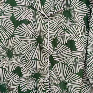 K&ouml;nnte beinhalten: Ein gr&uuml;n-wei&szlig;es Hemd mit Kn&ouml;pfen und einem floralen Muster. Das Hemd hat einen wei&szlig;en Saum um den Kragen und die Manschetten. Das Etikett auf dem Hemd lautet "FUTURE TEXTILE".