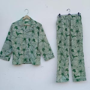 K&ouml;nnte beinhalten: Ein gr&uuml;nes und wei&szlig;es Pyjama-Set mit Blumenmuster. Das Oberteil hat einen Knopfleisten vorne und lange &Auml;rmel. Die Hose hat einen Kordelzugbund und eine gerade Beinpartie.